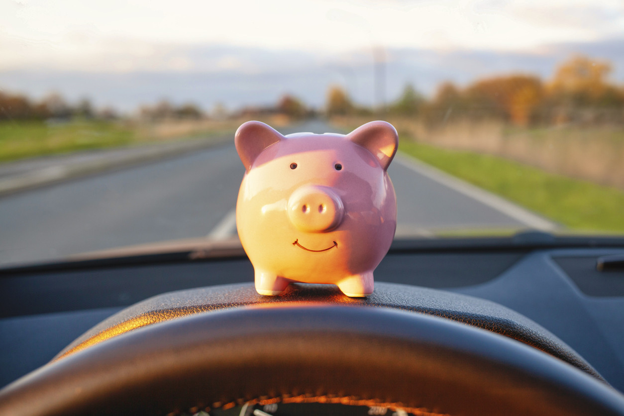 Pig money jar on a car dashboard representing getting a good deal for selling your car